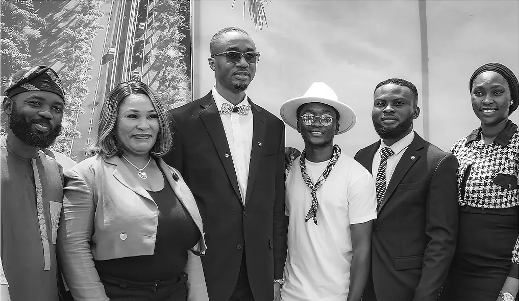 Chimezie Ikenga in a white hat with a group of five other people in front of the Tri-Tower site hoarding in Abuja