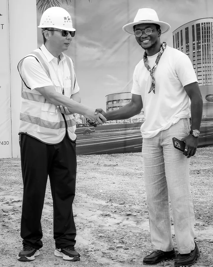 Chimezie Ikenga shaking hands with a man in a white hard hat and safety vest on the Tri-Tower site
